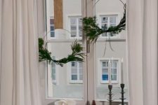 minimal holiday wreaths of metal forms, greenery and burlap bows are cool to decorate a Christmas window