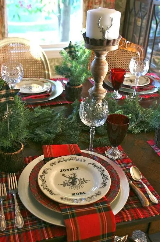 plaid mats and plates, an evergreen garland, deer candles, red glasses for a traditional feel