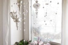 refined vintage Christmas window styling with beads, rhinestones, silver ornaments and a cage and some blooms on the windowsill
