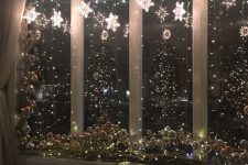 shiny Christmas window decor with lights, light stars and some silver ornaments on the windowsill