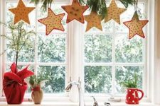 star-shaped cookies, evergreens on a branch are a cool way to style a window for Christmas