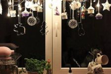 window Christmas decor of a branch with clay ornaments, cookie cutters, lights and mini houses and acupcakes is chic