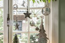 window Christmas decor with fresh greenery, silver and white ornaments, pretty wooden ornaments and mini trees