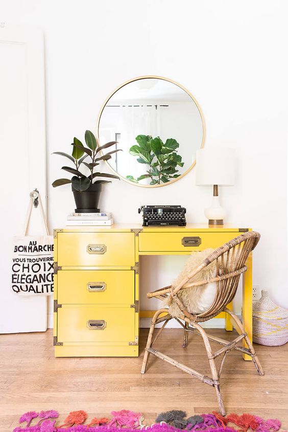 a vintage yellow desk, a rattan chair and a colorful rug add whimsiness to the space and make it bright and fun