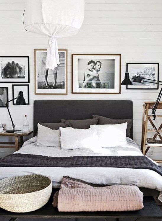 a Nordic black and white bedroom with a black bed, a gallery wall, mismatching wooden nightstands