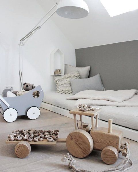 a Nordic kids’ room with a low bed, a floor lamp, some simple and wooden toys looks airy and very serene
