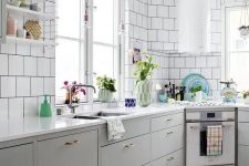 a Nordic kitchen with grey lower cabinets, white square tiles on the walls, a round hood and open shelves is lovely