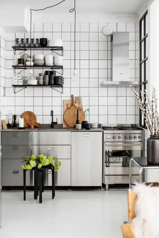 a Nordic kitchen with stainless steel cabinets and appliances, a shelving unit and a white square tile backsplash