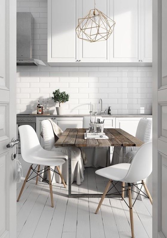 a Nordic kitchen with white cabinets and tiles, a rough wooden table, modern white chais and a geometric chandelier