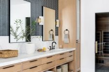 a Scandinavian bathroom with navy skinny tiles and marble ones, a stained vanity, towels, greenery and a pouf