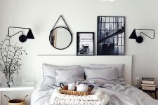 a Scandinavian bedroom with a bed styled with grey bedding, mismatching nightstands, a basket and a gallery wall on the mantel
