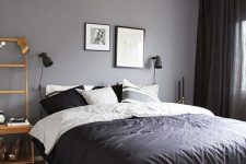 a Scandinavian bedroom with a grey accent wall, a bed with monochromatic bedding, a stained nightstand and a woven lamp