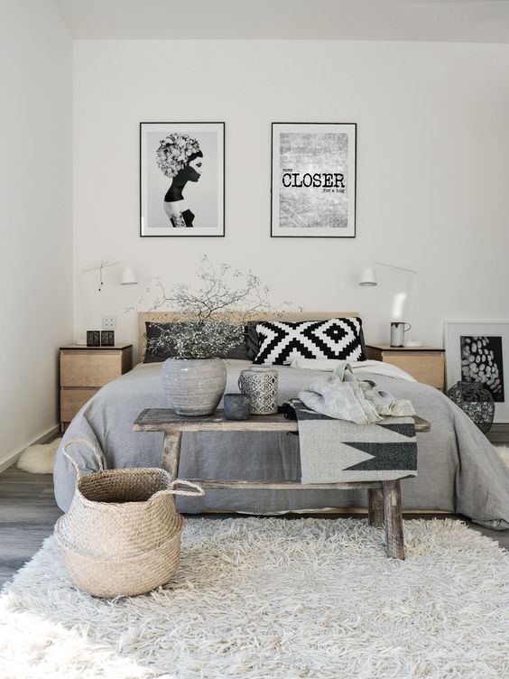 a Scandinavian bedroom with stained furniture, grey textiles, baskets, a gallery wall and white sconces