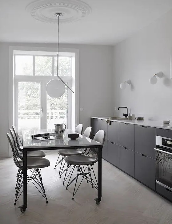 A Scandinavian black one wall kitchen with a white coutnertop and black fixtures plus some sconces and a pendant lamp.