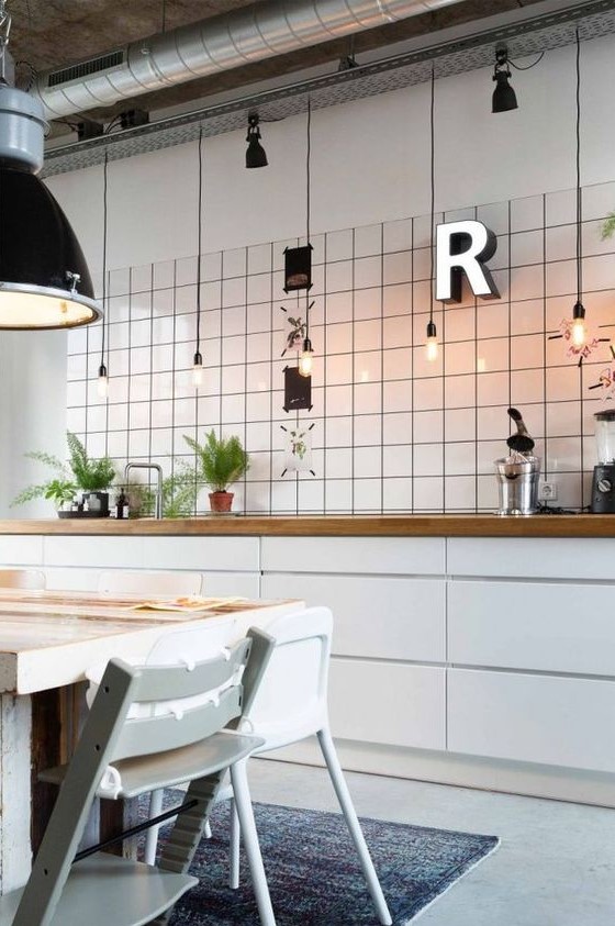 a Scandinavian kitchen with sleek white cabinets, butcherblock countertops, white square tiles on the wall