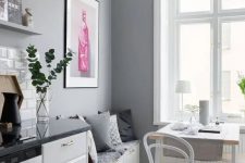 a Scandinavian kitchen with white shaker cabinets, grey countertops, grey walls and a small dining zone