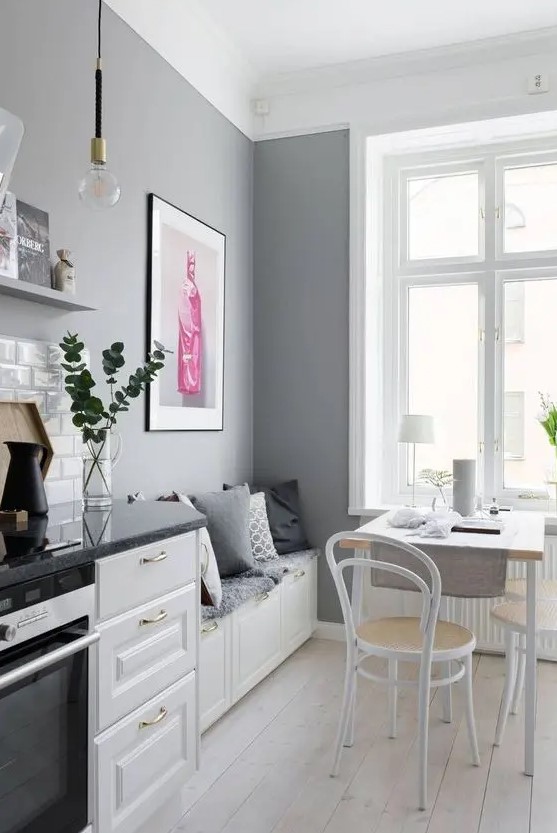 a Scandinavian kitchen with white shaker cabinets, grey countertops, grey walls and a small dining zone