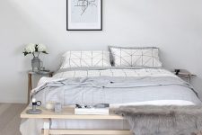 a casual Nordic bedroom in off-whites, with a wooden bench, a comfy bed and a pendant lamp for a modern look