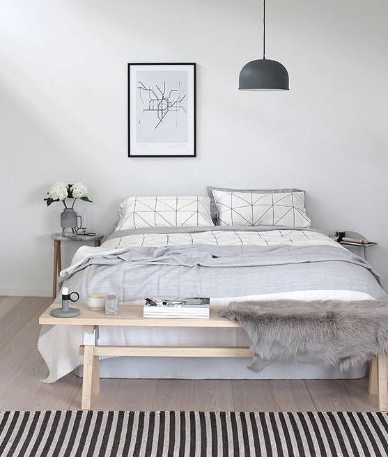 A casual Nordic bedroom in off whites, with a wooden bench, a comfy bed and a pendant lamp for a modern look