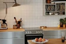 a catchy Nordic kitchen with sleek grey cabinets, butcherblock countertops, a white square tile backsplash and a shelf