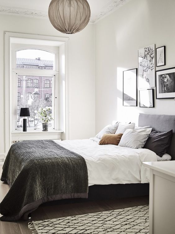a catchy Scandinavian bedroom with a grey bed and monochromatic bedding, a gallery wall, a pendant lamp and some decor