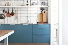a catchy blue Scandinavian kitchen with only lower cabinets, a white square tile backsplash, an open shelf and a stained kitchen island