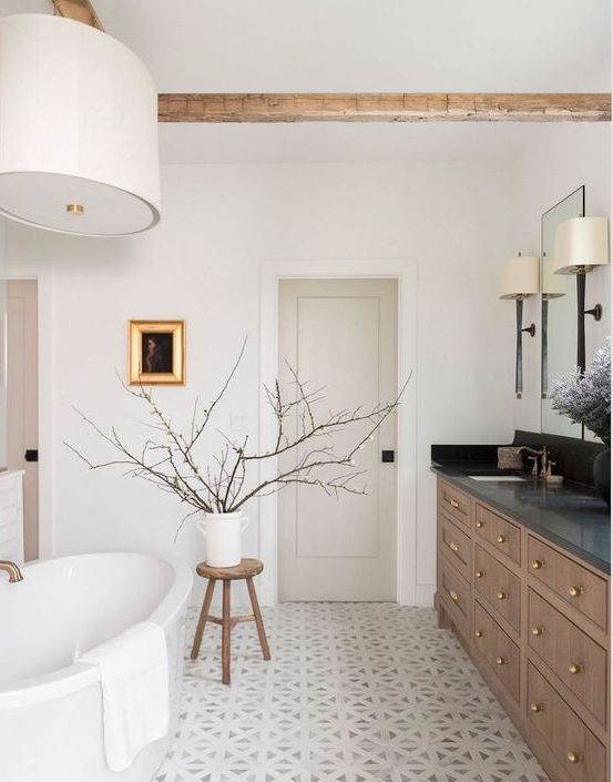 a chic Scandinavian bathroom with a stained vanity, an oval tub, a pendant lamp, a stool with branches and lamps