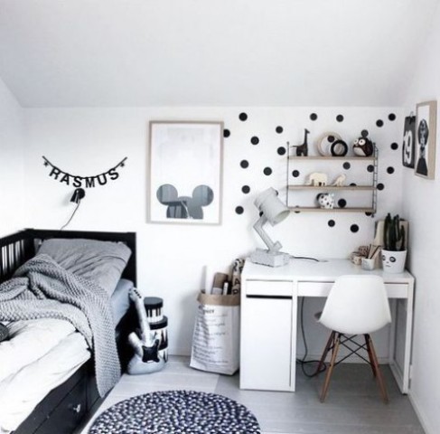a chic Scandinavian bedroom for a kid   a black bed with storage, a white desk and a chair, a shelf, some artworks and a polka dot touch on the wall