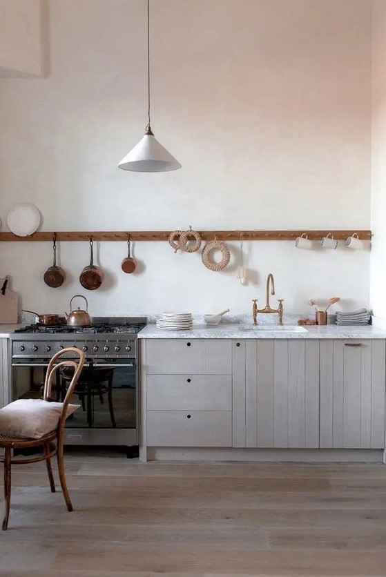 a chic blonde wood one wall kitchen with a white stone countertop and a long holder with mugs and pans