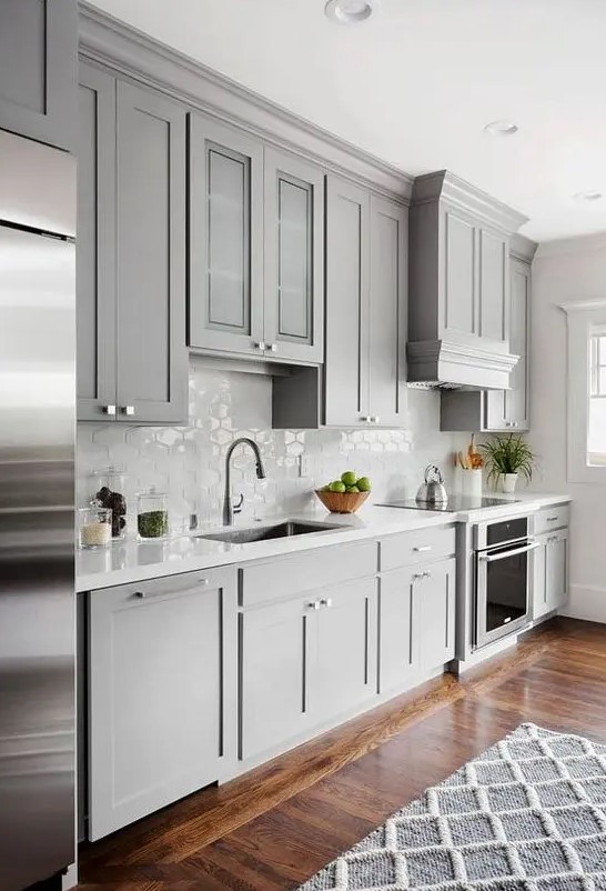 A traditional kitchen with light grey cabinets, a geometric rug, and a white hexagon tile backsplash. Combine light grey and white for a timeless color scheme and use geometric patterns to add visual interest.