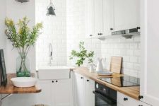 a chic white kitchen with butcherblock countertops, a folding table and stools and vintage pendant lamps