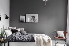 a contemporary Scandinavian bedroom with a dark wall, monochromatic bedding, lamps and lights and a grey rug