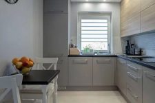 a contemporary grey and light stained kitchen with black countertops and a small eating space