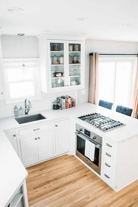 a contemporary white kitchen with white countertops and a backsplash is a small and cozy space