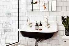 a contrasting modern bathroom with white square tiles and hex tiles on the floor, a black wall-mounted sink, a mirror and some potted plants