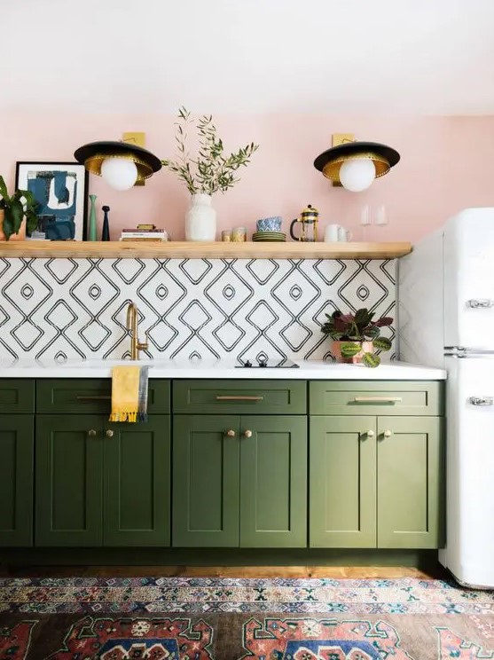 This kitchen features a long open shelf perfect for art and decor. Lower green cabinets provide a lively touch. The geo tile backsplash adds a unique pattern.