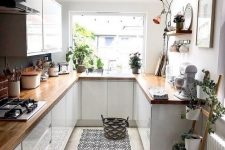 a cool contemporary U-shaped kitchen with sleek white cabinets, butcherblock countertops, a bold rug and potted plants