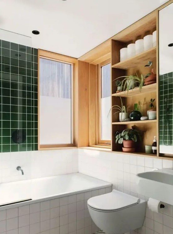 a cool modern bathroom with square green and white tiles, geo tiles on the floor, a stained shelving unit and white appliances