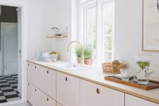 a delicate blush kitchen with only lower cabinets and white countertops plus much natural light