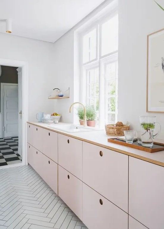 A delicate blush kitchen with only lower cabinets and white countertops plus much natural light.