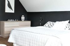 a dreamy attic bedroom with black walls and a white ceiling, a white bed with neutral bedding and a stainder dresser