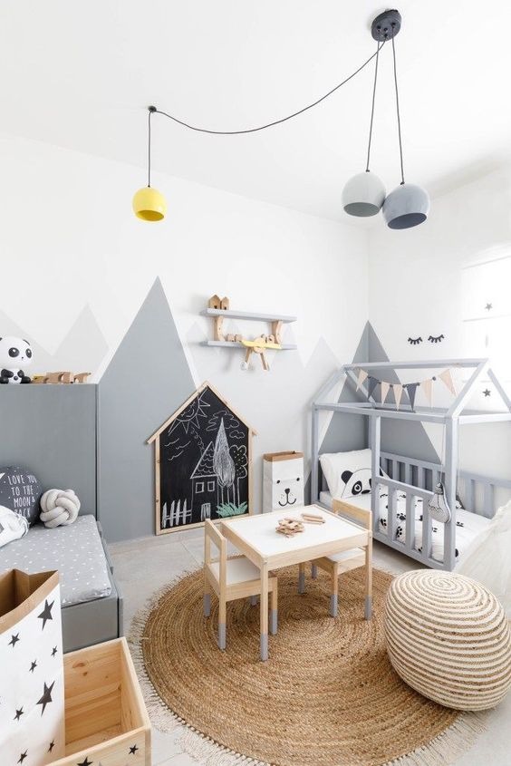 a fun and cool Scandinavian kids' room with two beds, walls with mountain art, pendant lamps, wooden boxes with stars