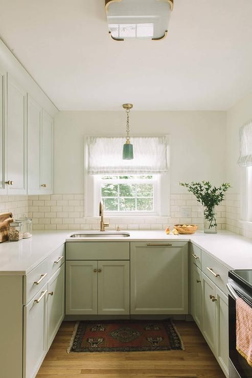 a green farmhouse kitchen with shaker cabinets, a white subway tile backsplash, white stone countertops and a green pendant lamp