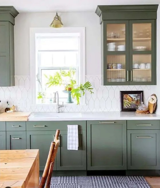 A green one wall kitchen with a pretty white tile backsplash, a white countertop and brass touches plus a printed rug.