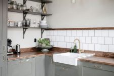 a grey L-shaped Scandinavian kitchen with a white square tile backsplash, open shelves, pendant lamps and a stained table