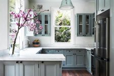 a grey U-shaped kitchen with shaker cabinets, white stone countertops, windows for natural light and some blooms