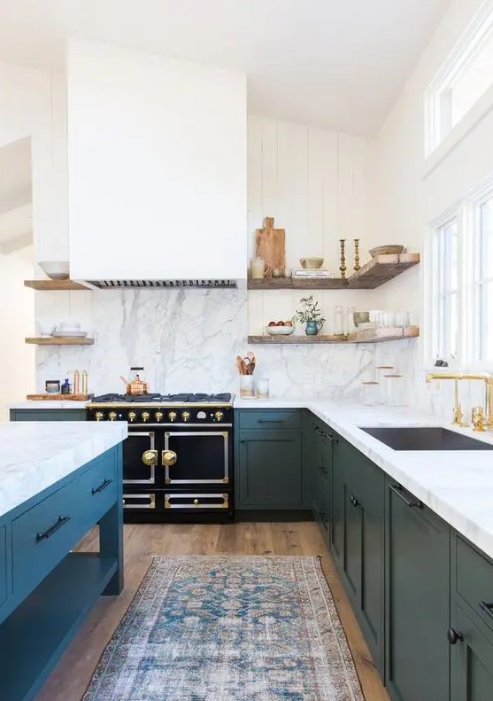 A large navy and white L shaped kitchen with white stone countertops and a backsplash plus a matching kitchen island