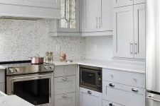 a light grey farmhouse kitchen with a mosaic tile backsplash and white stone countertops is elegant and cool