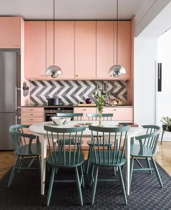 A light pink mid-century modern kitchen with a graphic tile backsplash and a dining zone in blue right here.