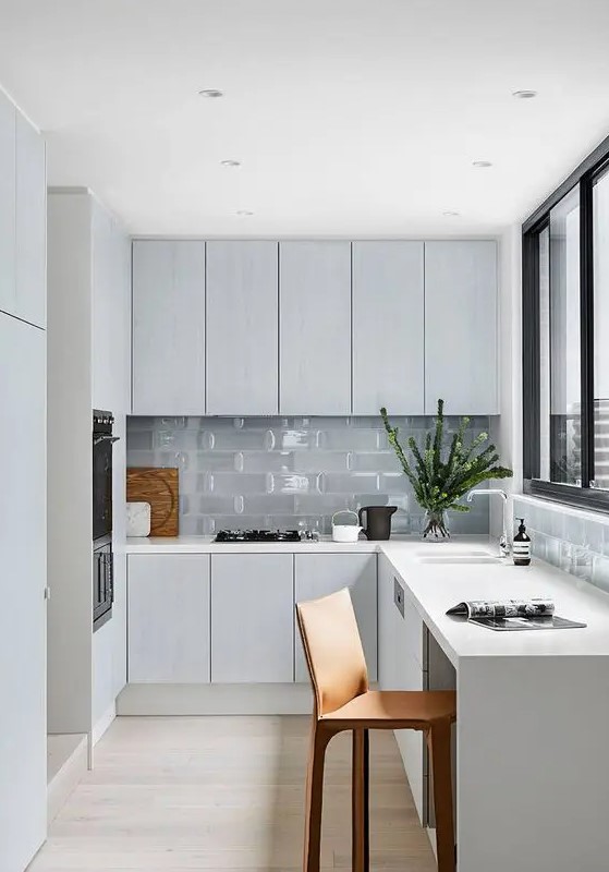 A minimal Nordic L shaped kitchen with glass tiles and a window with a view is a lovely idea
